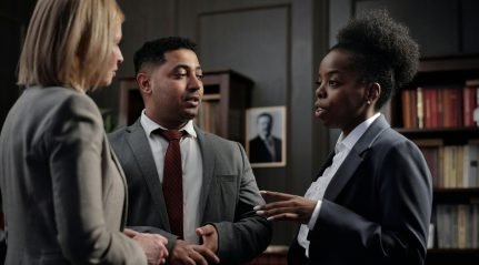 Three professionals in suits talking in a library