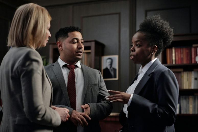Three professionals in suits talking in a library