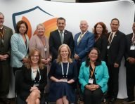 A group of about a dozen men and women in business dress posing for a photograph at an event