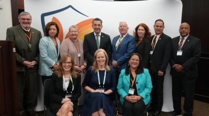 A group of about a dozen men and women in business dress posing for a photograph at an event