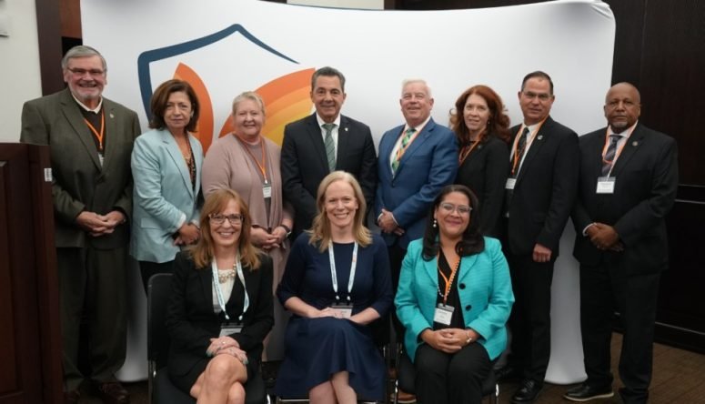 A group of about a dozen men and women in business dress posing for a photograph at an event