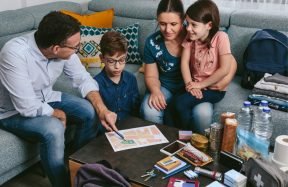 A family of four on a sofa going through papers and a first-aid kit on the coffee table