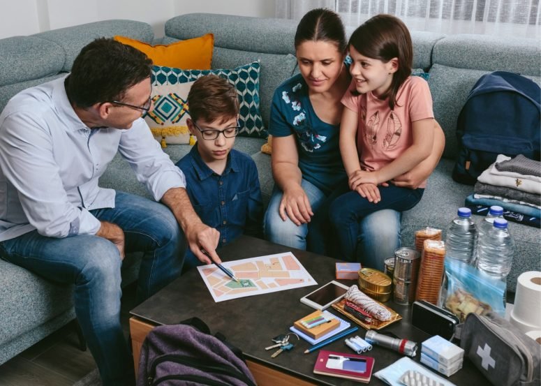 A family of four on a sofa going through papers and a first-aid kit on the coffee table